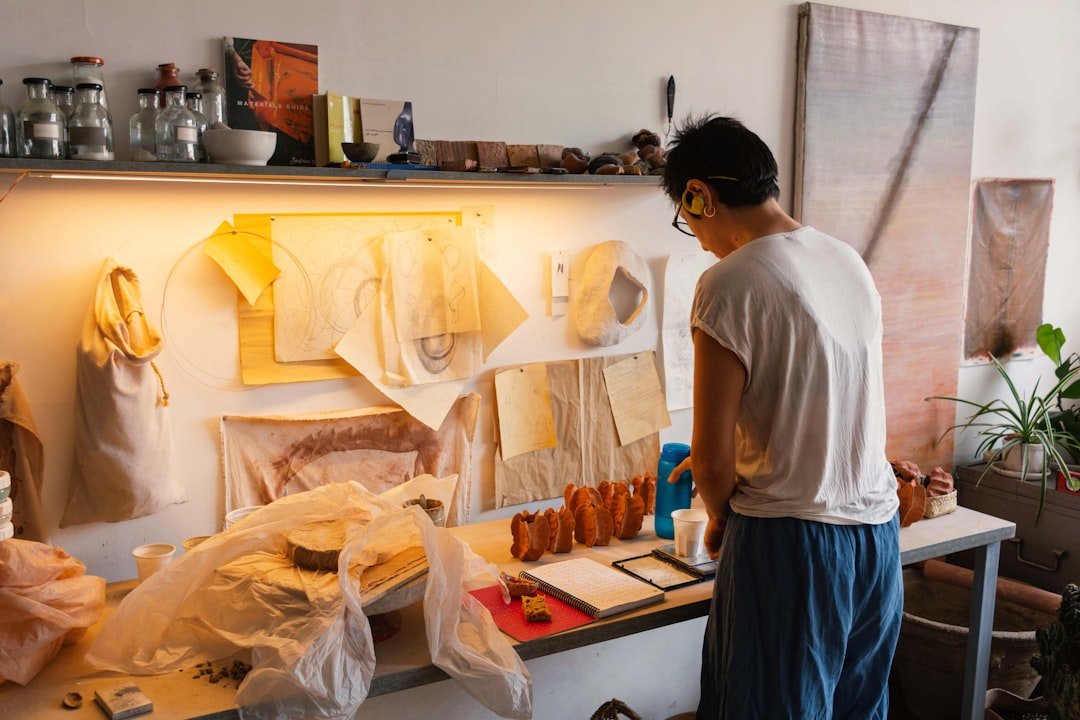 Artist working independently at a desk filled with creative materials