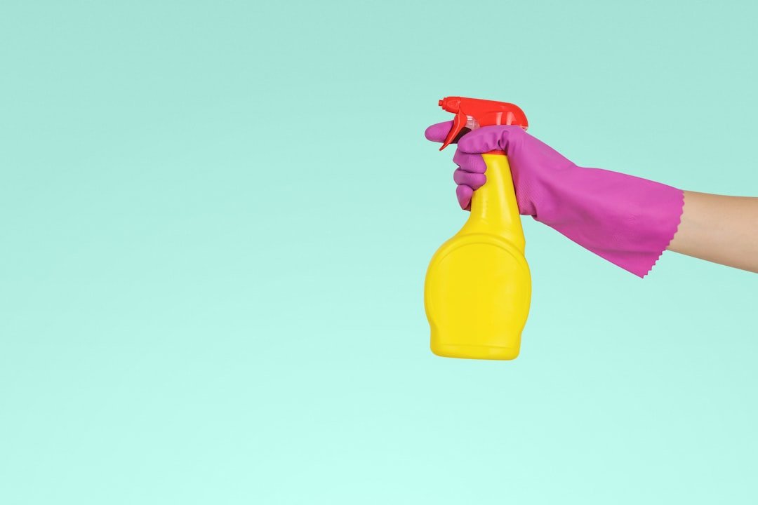 Cleaner wiping a kitchen surface with a yellow spray bottle