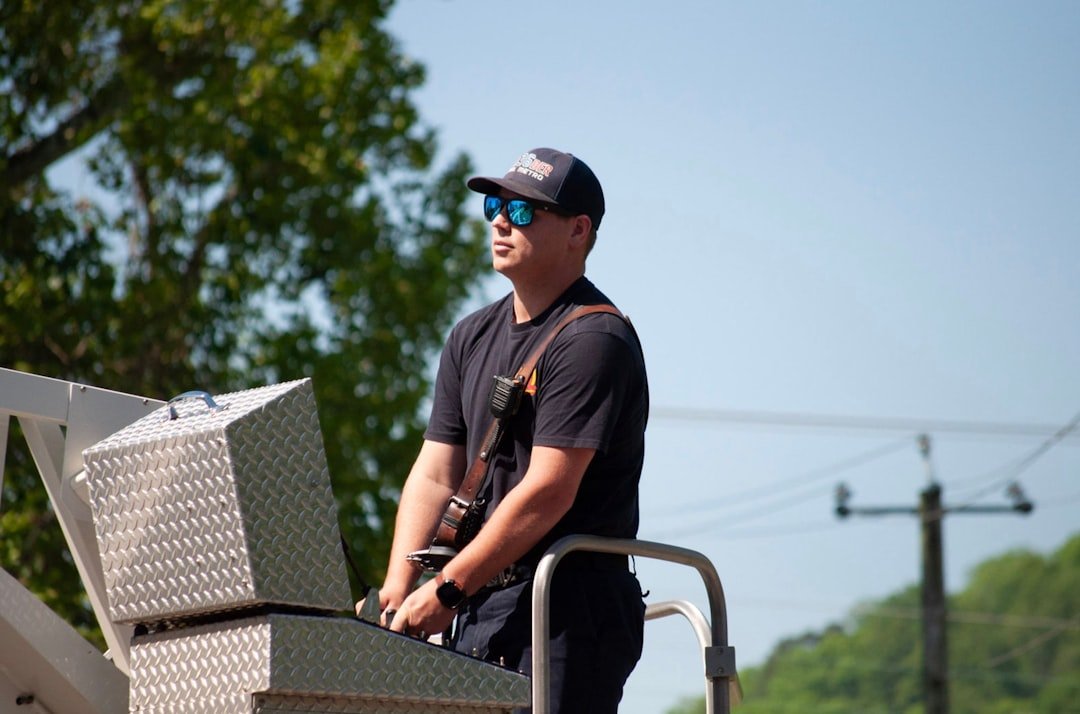 Local service worker using a ladder beside a work vehicle