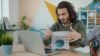 Small business owner reviewing paperwork while working at a laptop